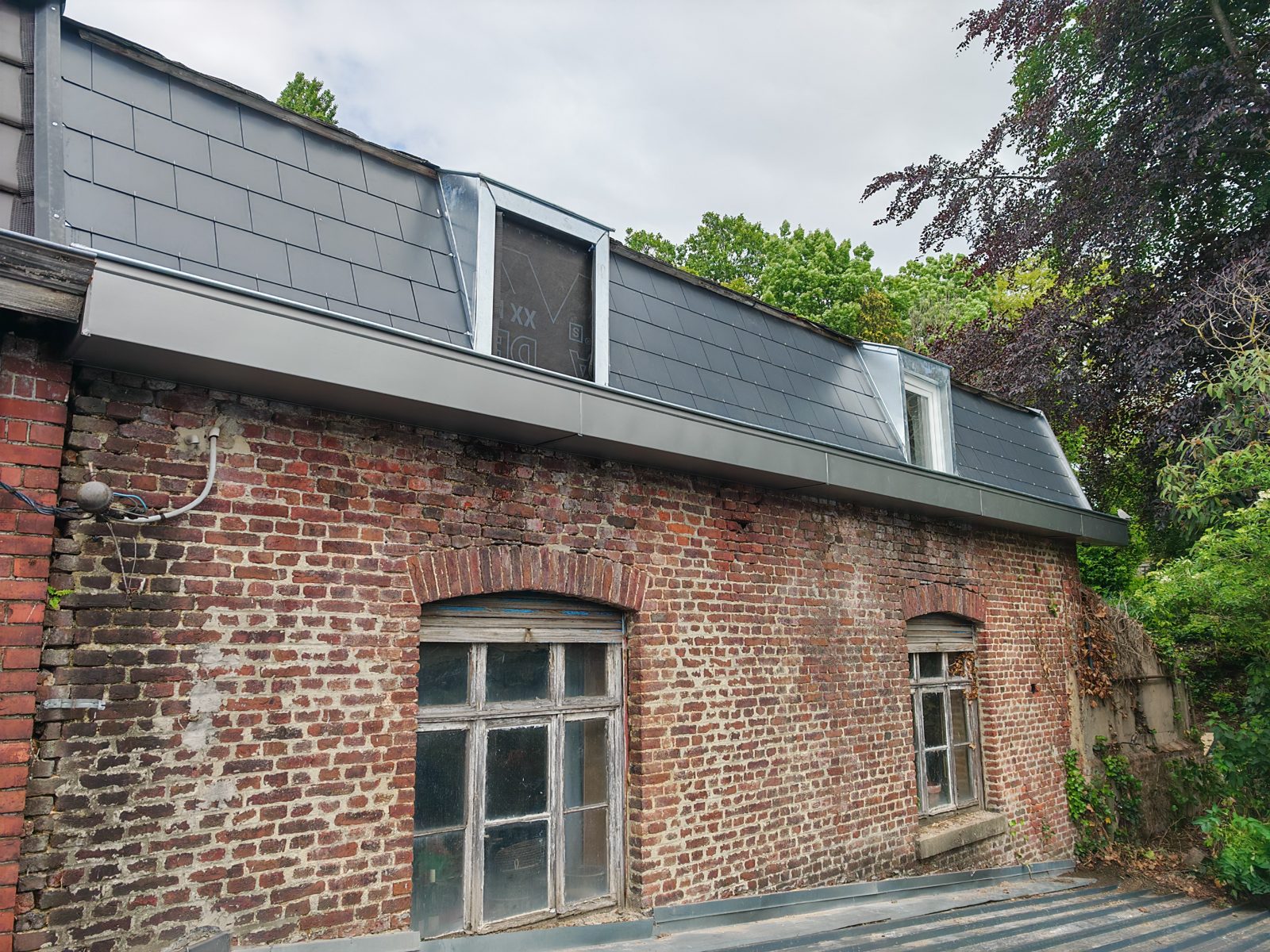 Toiture en ardoise rénovée sur un bâtiment en brique par SkySafe Toitures près de Liège